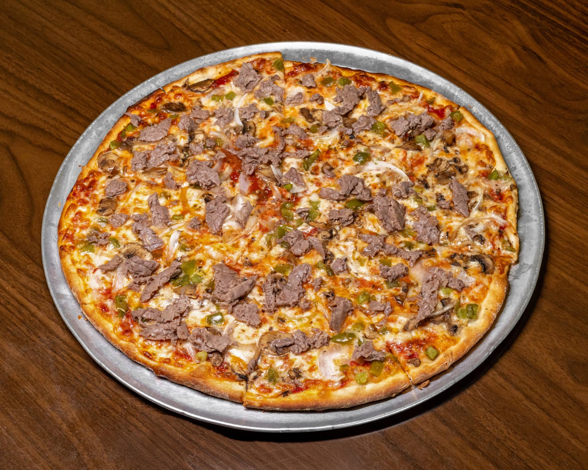 Cheesesteak pizza with shaved steak, peppers and onions