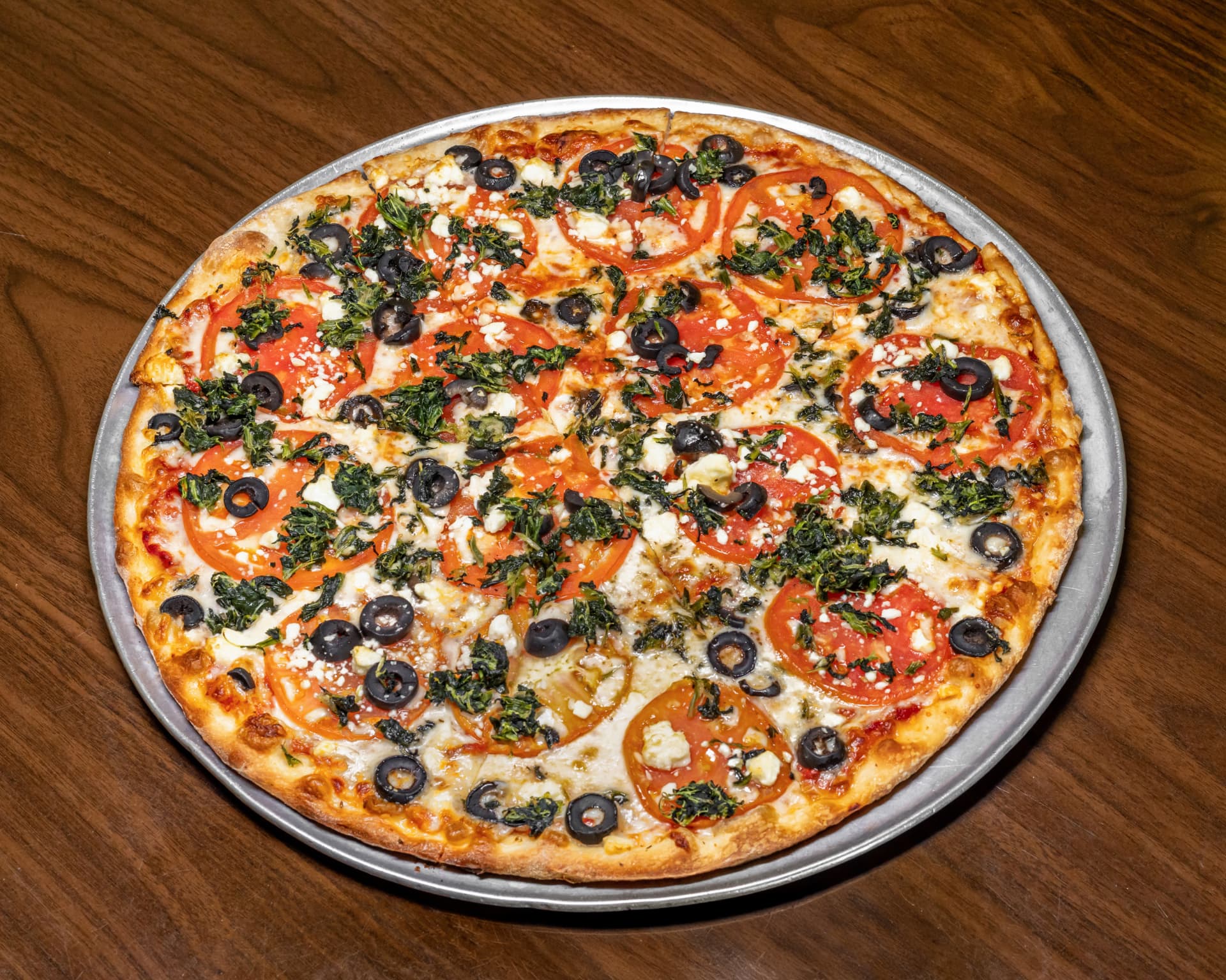 Greek pizza with tomatoes, spinach, black olives and feta
