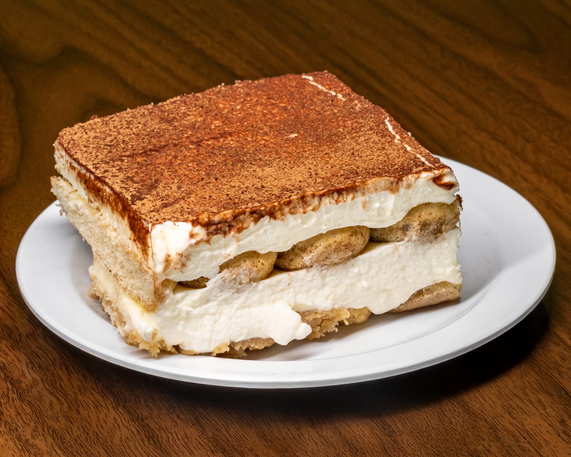 Slice of homemade Italian tiramisu dusted with cocoa